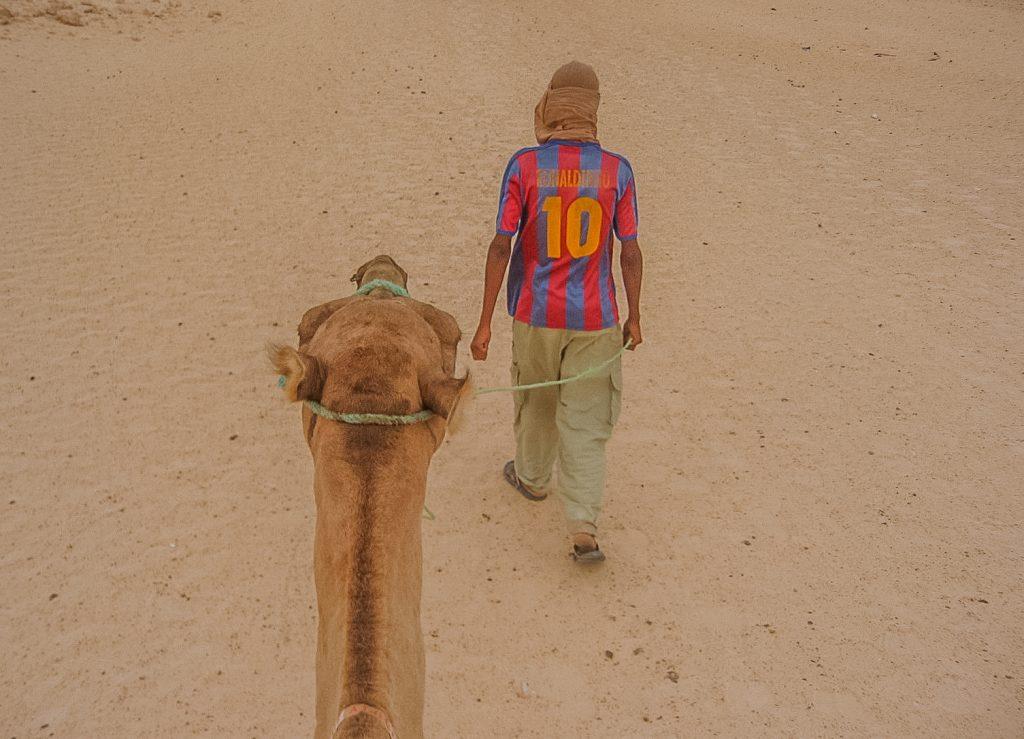Tuareg nomads leading a camel in the Sahara Desert